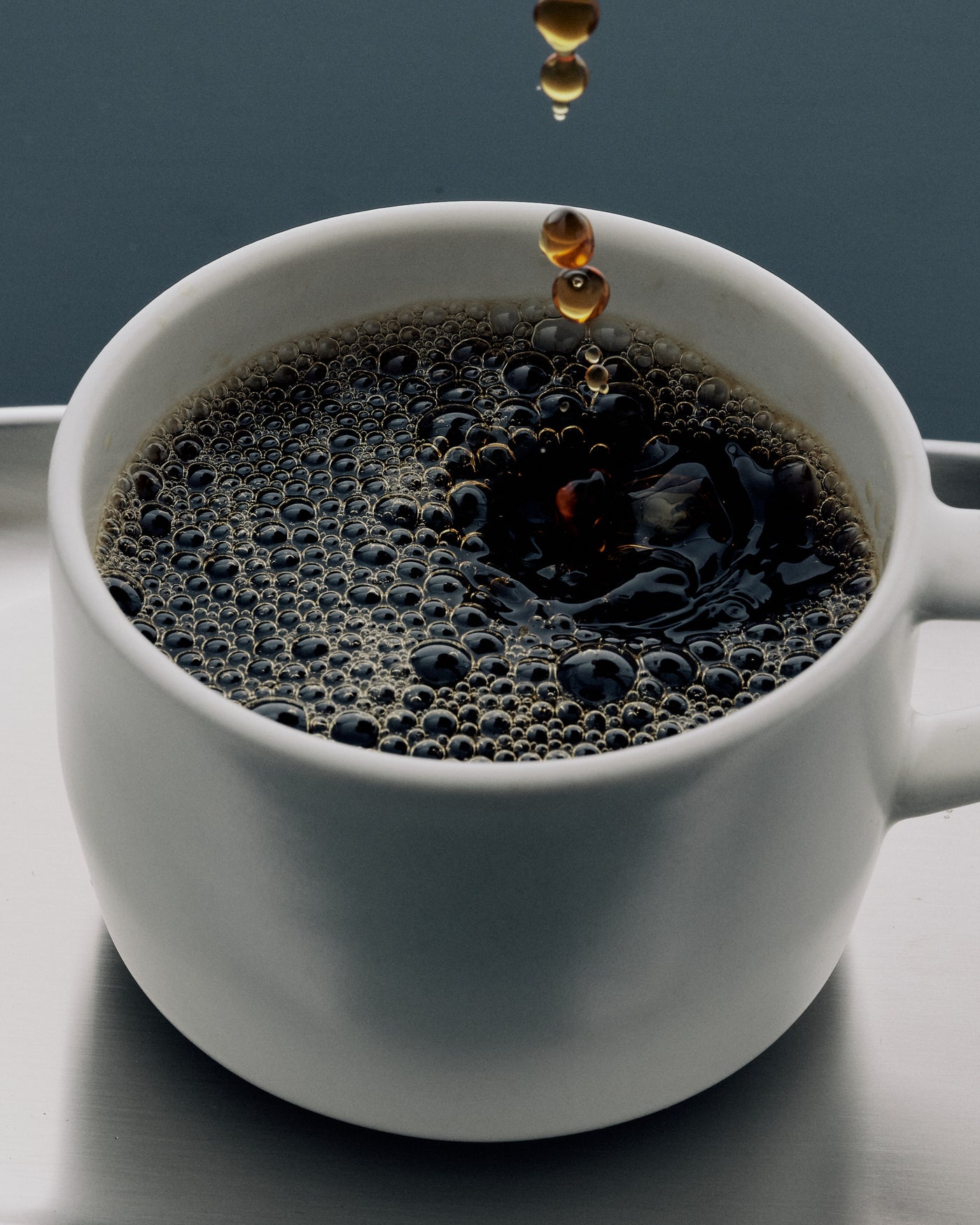 Freshly brewed black coffee dripping into a white cup